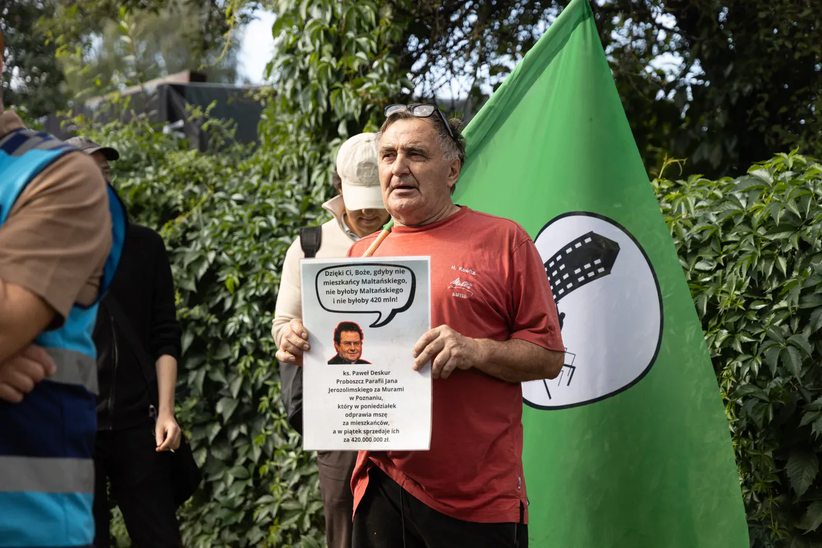 Uczestnik protestu z transparentem pod flagą stowarzyszenia (09.57)