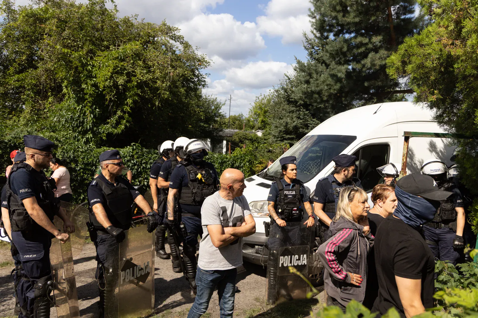 Furgonetka policyjna i funkcjonariusze w kaskach wjeżdżający na osiedle