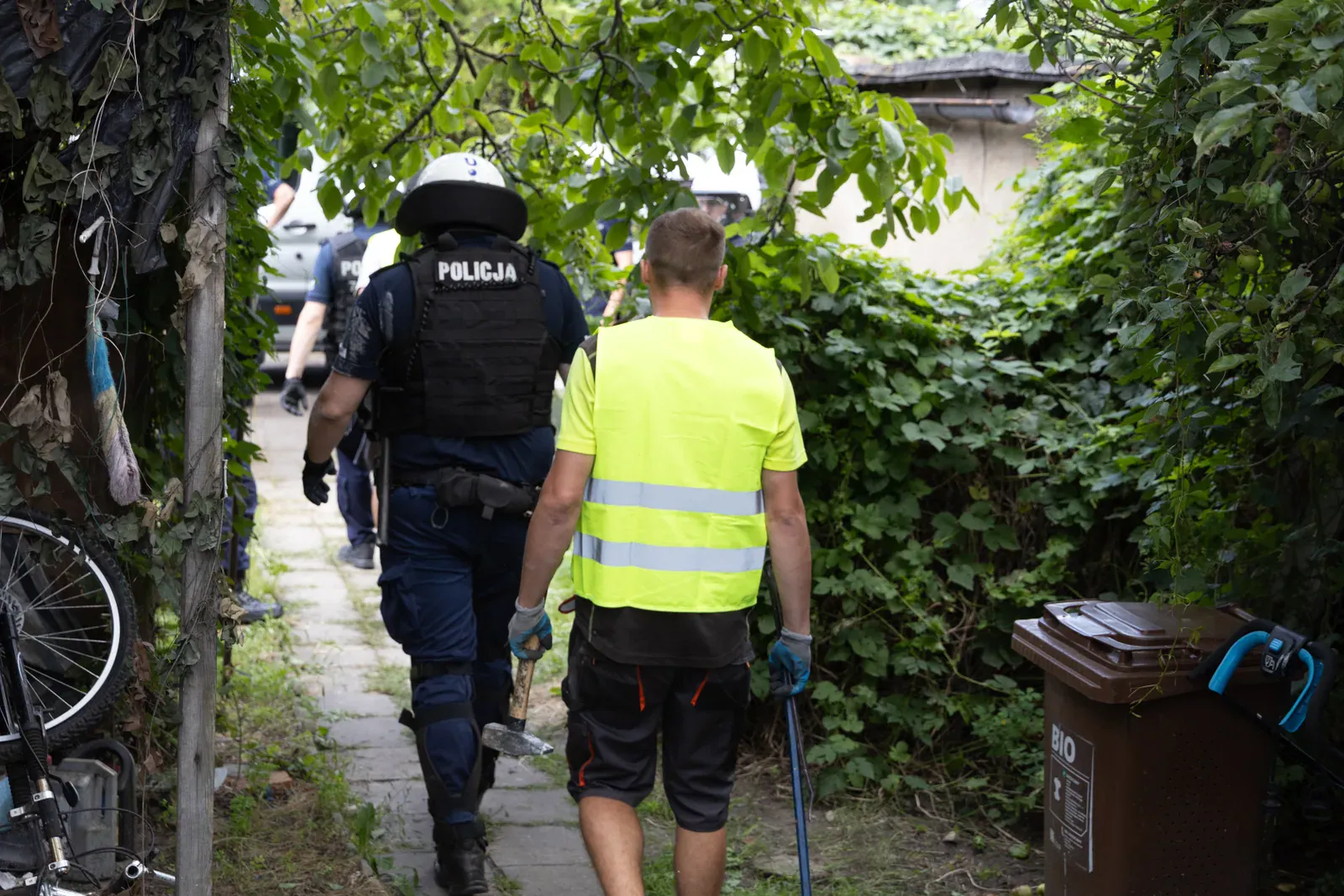 Ekipa w kamizelkach odblaskowych wchodzi do ogrodu (11.09)
