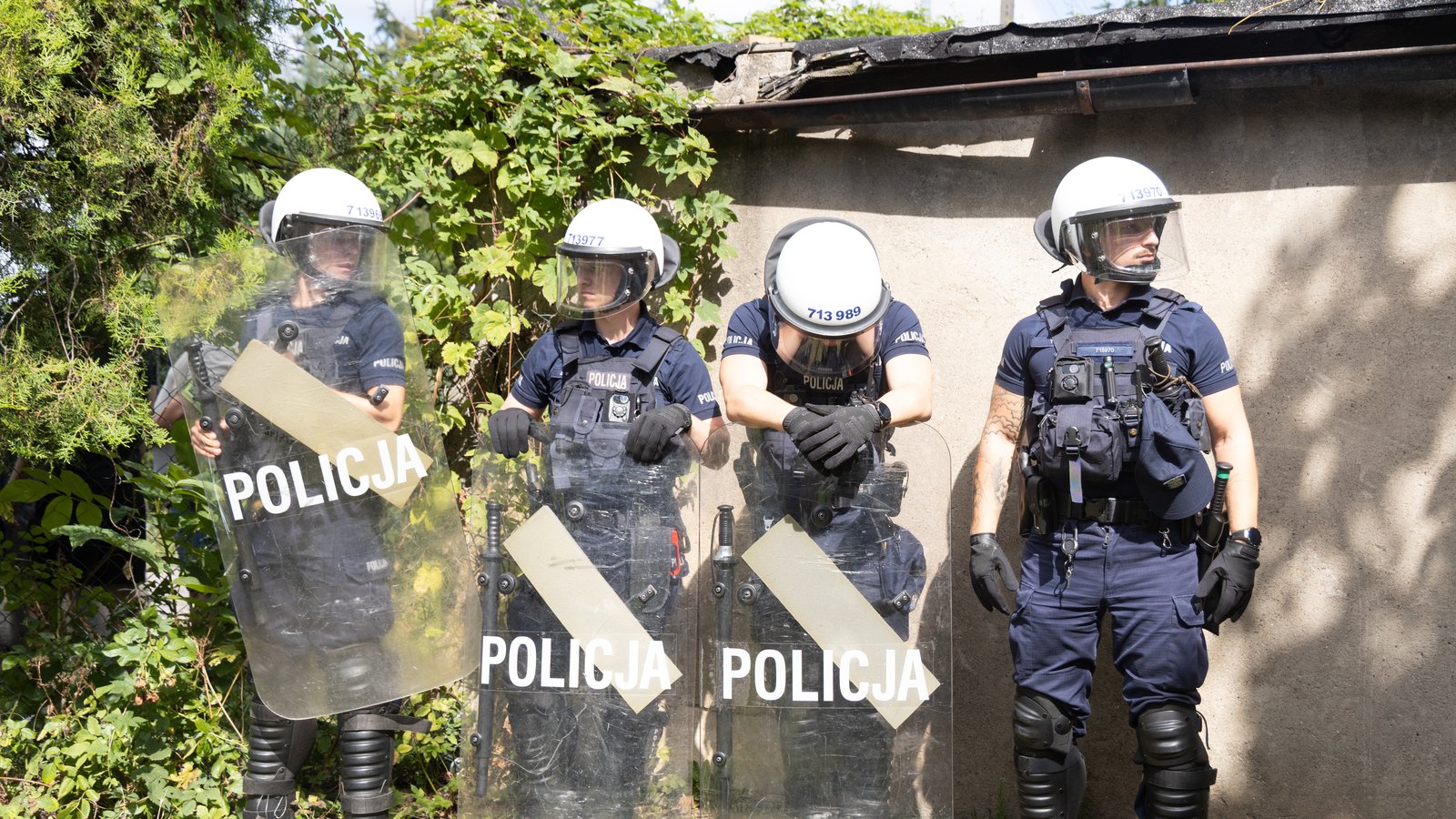 Kordon policjantów z tarczami na wąskiej alejce między ogrodami na osiedlu Maltańskim w Poznaniu