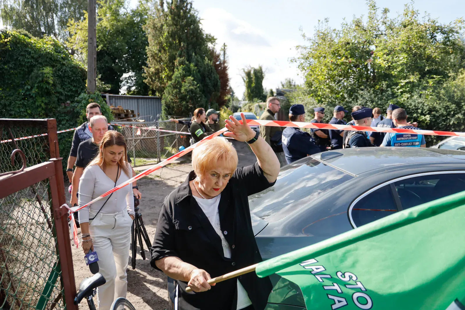 Mieszkanka z flagą stowarzyszenia przechodzi pod policyjną taśmą (9.57)