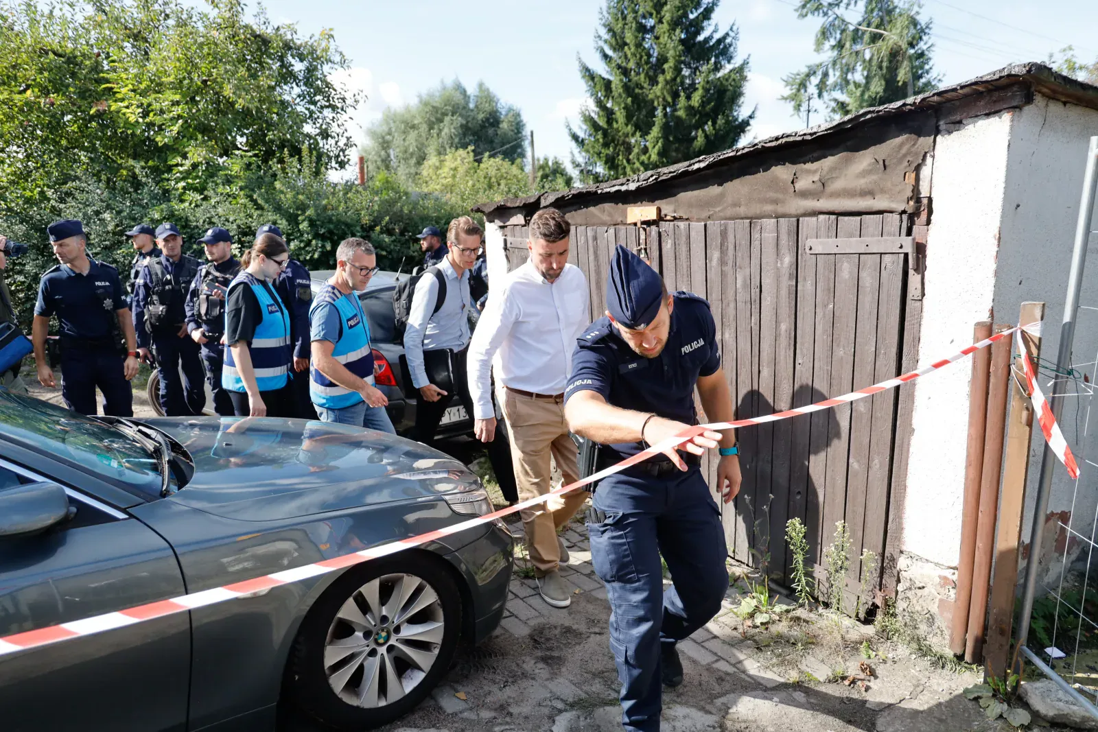 Policjant rozciąga taśmę wokół terenu czynności (9.57)