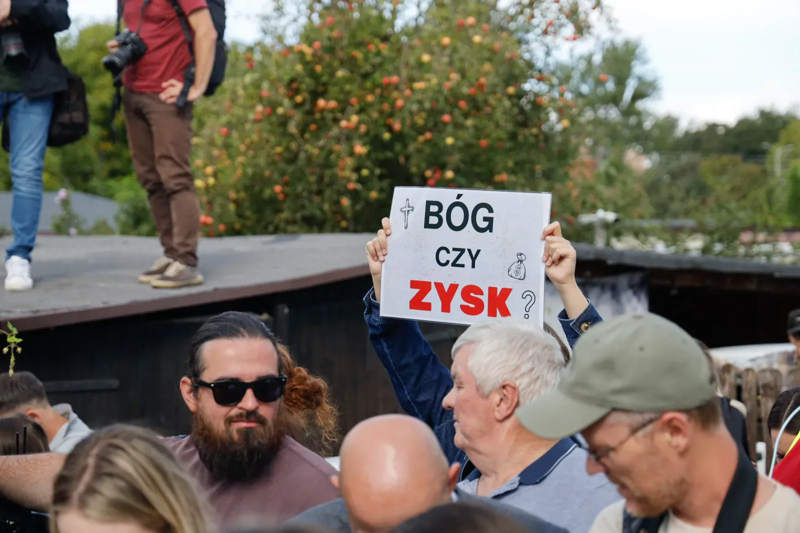 Plansza „Bóg czy zysk?” nad tłumem (10.41)