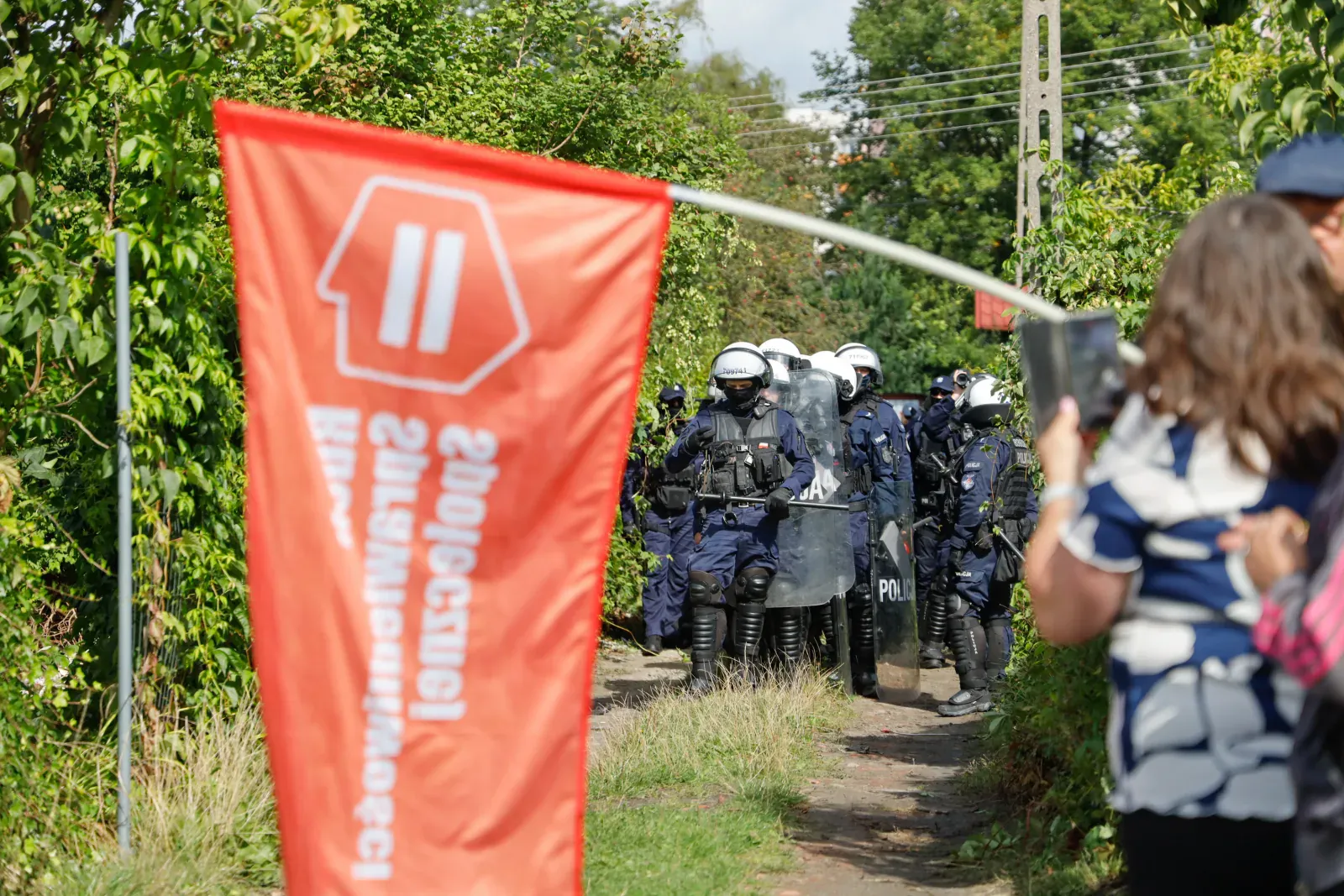 Funkcjonariusze z tarczami w alejce między ogrodami (11.18)