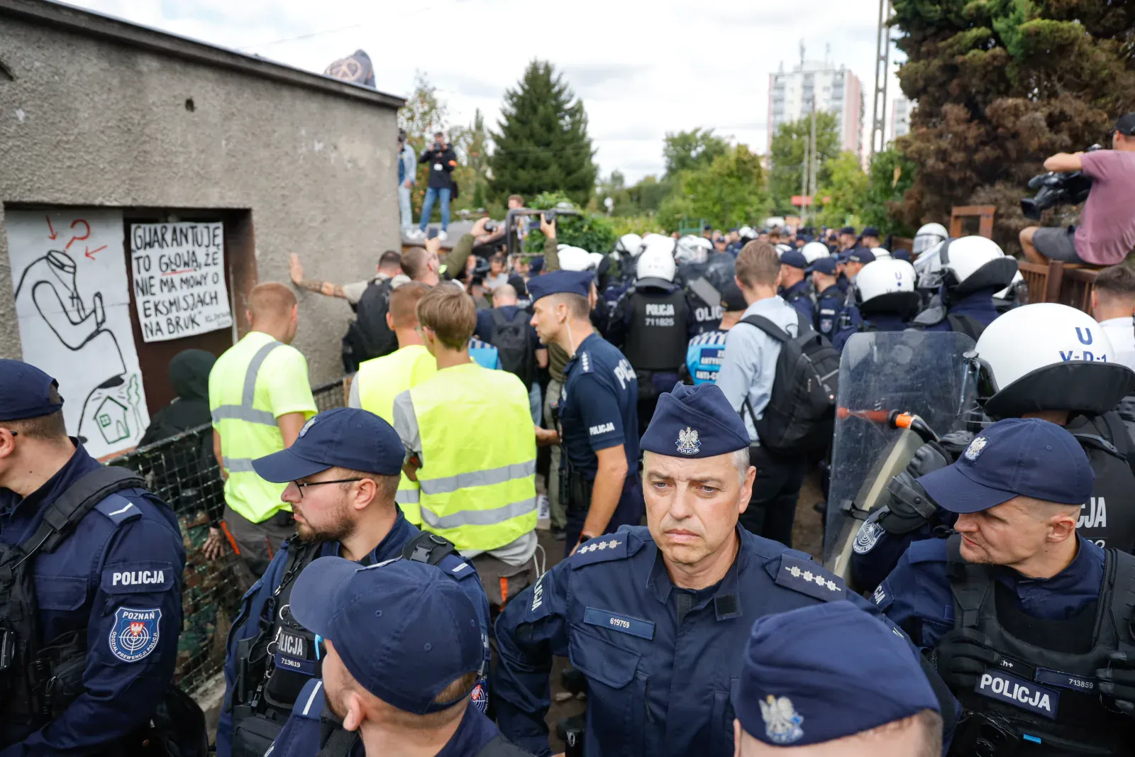 Policja i ekipa w kamizelkach przy domu (12.00)