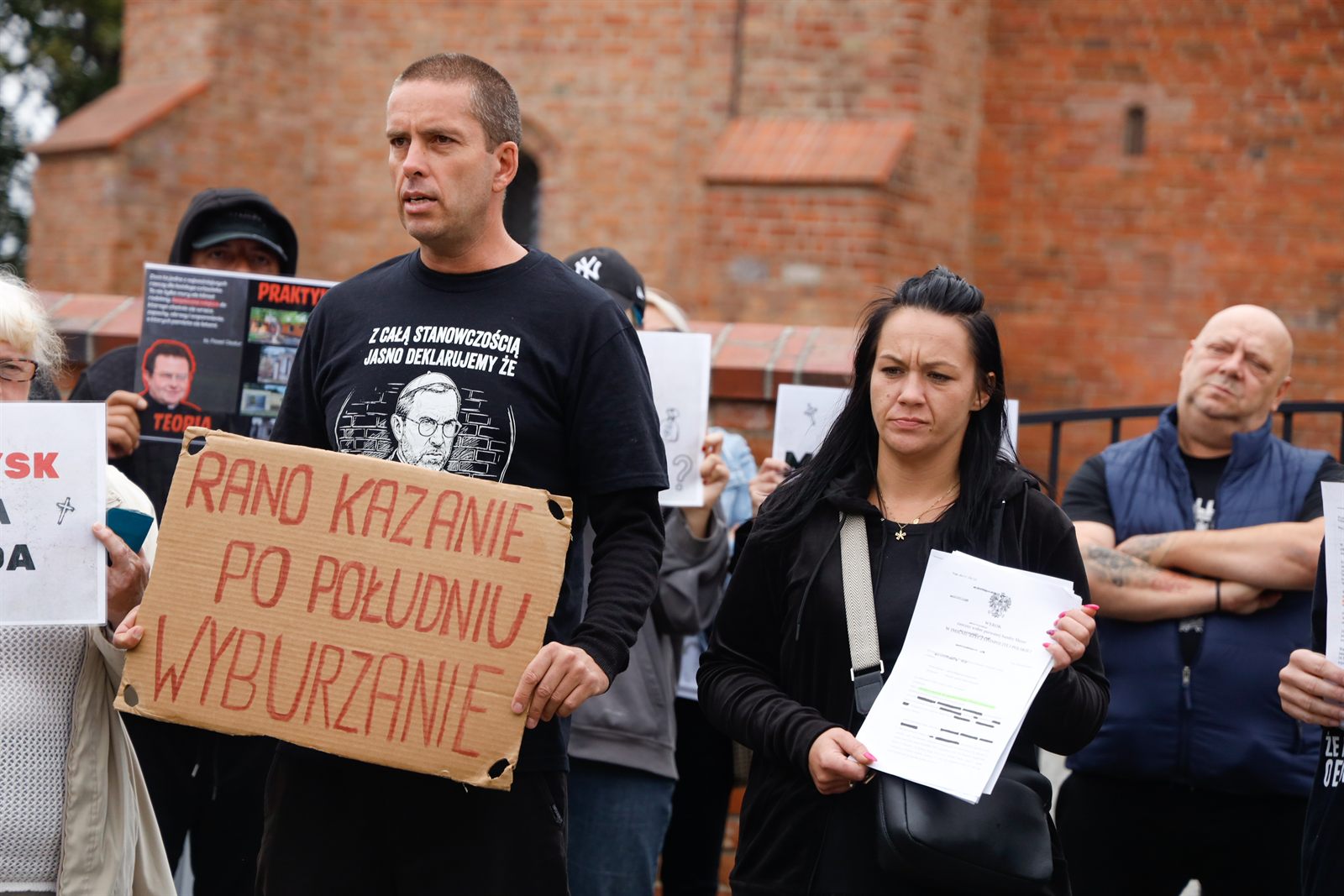 Tabliczka protestu i wyrok eksmisyjny w rękach mieszkanki