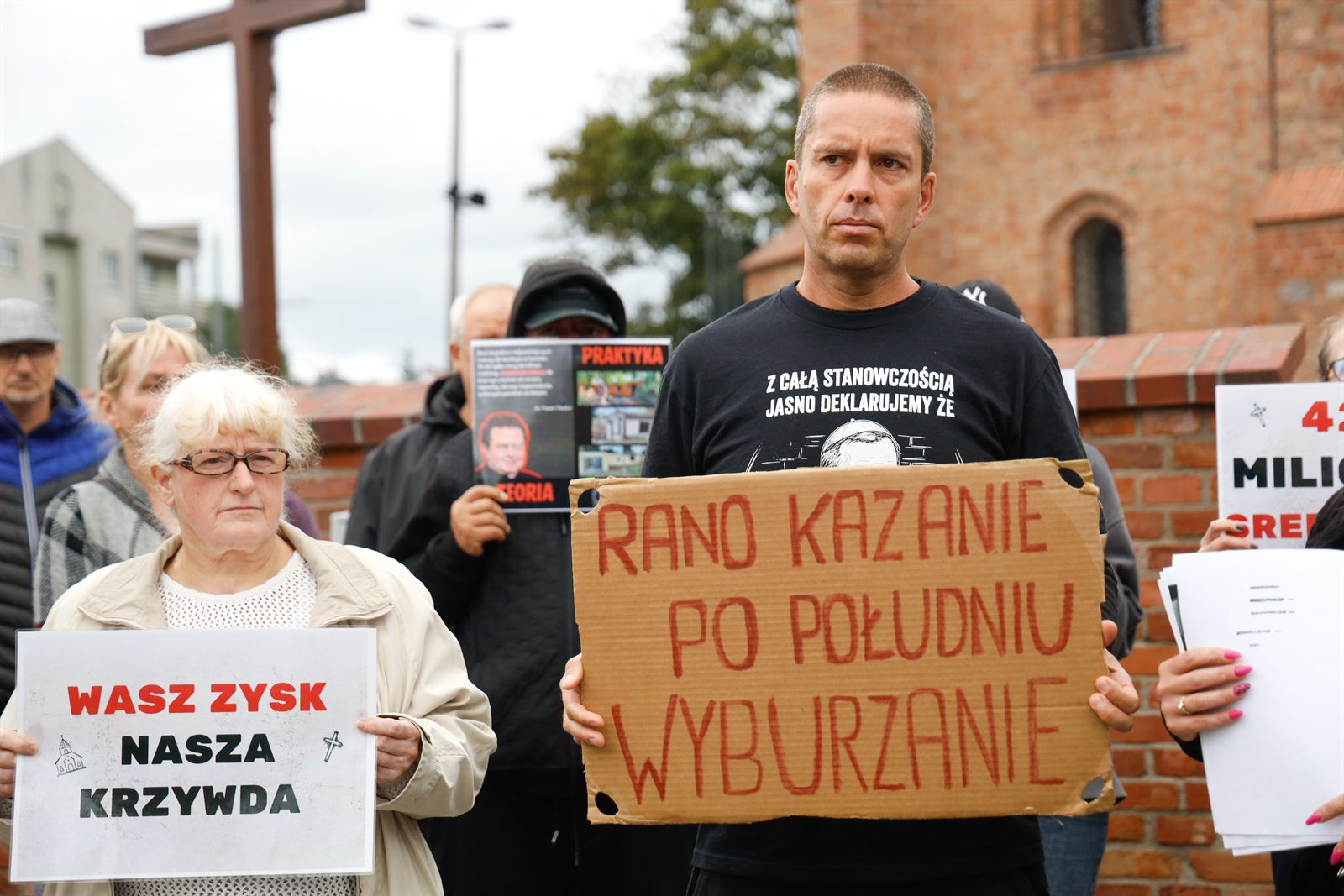 Portret uczestnika z tablicą „Rano kazanie, po południu wyburzanie”
