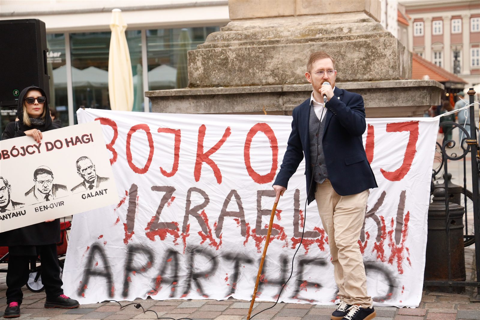 Przemówienie przed transparentem „Bojkotuj izraelski apartheid”