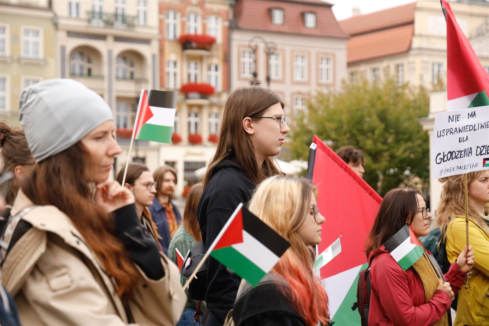 Uczestniczki z flagami, z tyłu plansza „Nie ma usprawiedliwienia dla głodzenia dzieci”