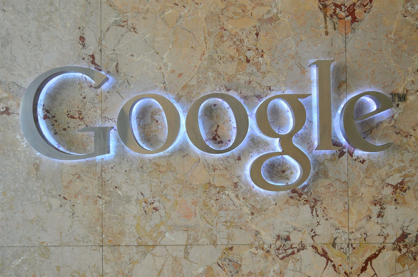 Podświetlone logo Google na marmurowej ścianie w biurze firmy
