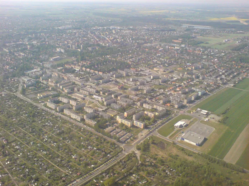 Ostrów Wielkopolski z lotu ptaka, osiedla bloków, ogródki działkowe i hala handlowa na skraju miasta