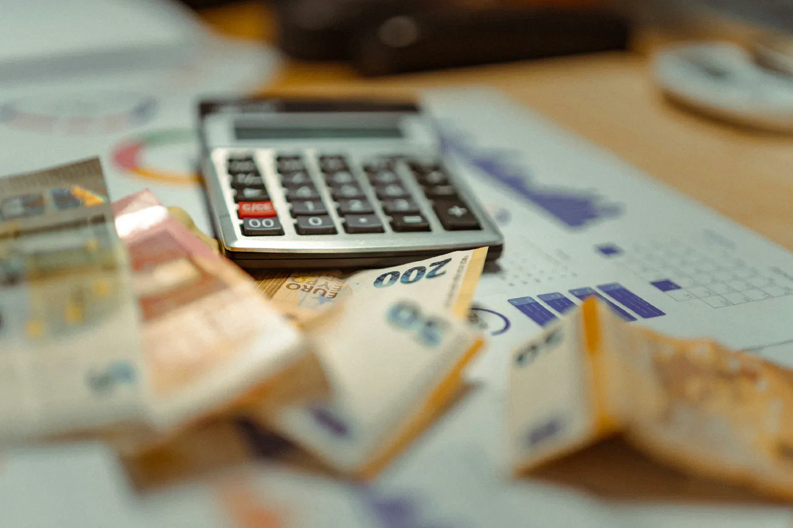 Kalkulator i banknoty leżące na wydrukach z wykresami finansowymi
