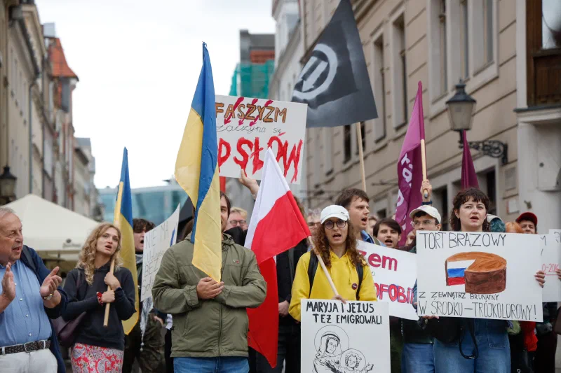 Uczestnicy i uczestniczki wydarzenia na Starym Rynku w Poznaniu z flagami Ukrainy i Polski oraz transparentem „Faszyzm zaczyna się od słów"