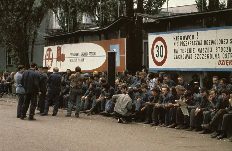 Strajkujący robotnicy czekają przed bramą Stoczni Gdańskiej 20 sierpnia 1980 roku, nad bramą napis „Dziękujemy za dobrą pracę".